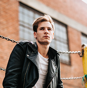 Portait of main in leather jacket in front of brick building